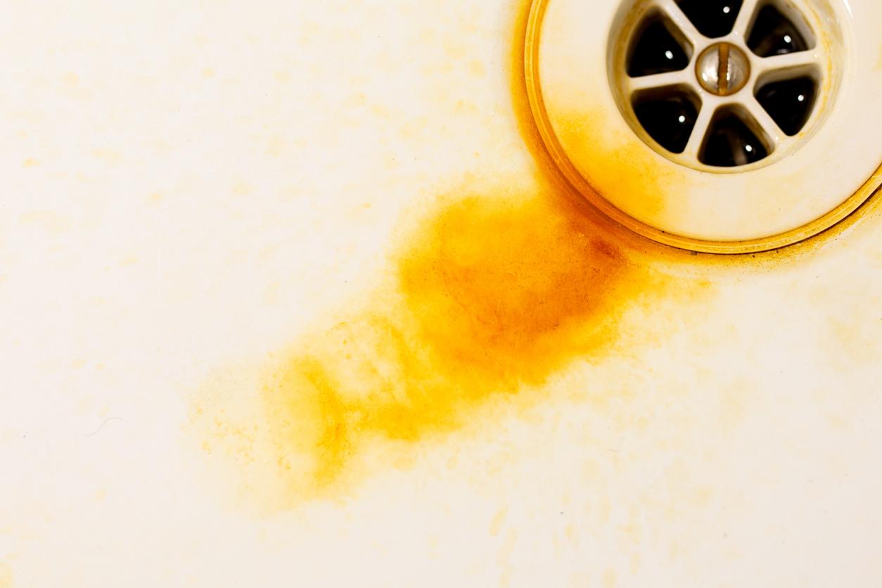 Orange rust stains in a sink by the drain caused by rusty water.