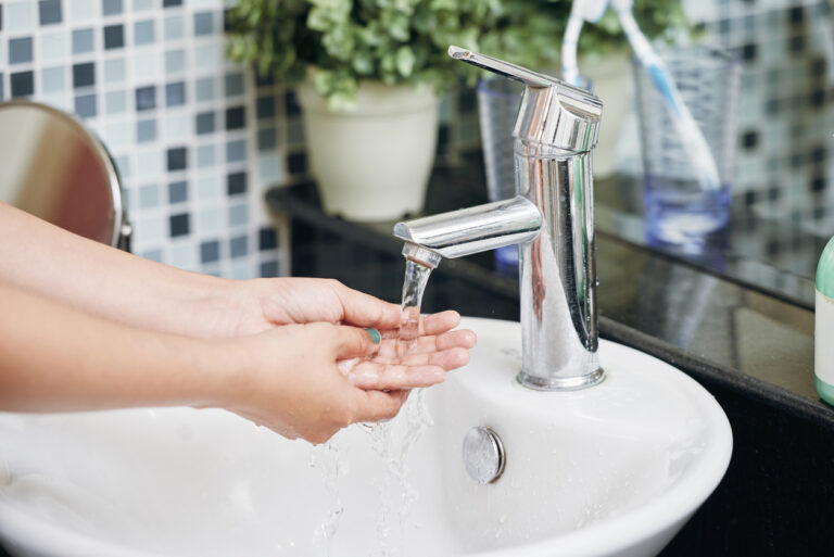 A woman washing her hands in a bathroom sink with soft water